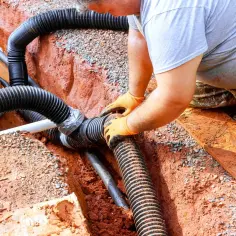 Instalator łączy rury odprowadzające wodę z rynien. Przepisy dotyczące odprowadzenia wody z rynien są ważne dla prawidłowego drenażu.