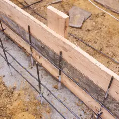 Drewniane szalunki i zbrojenie przygotowane do betonowania ławy fundamentowej. Izolacja ławy fundamentowej jest kluczowa dla trwałości budynku.
