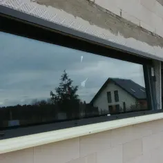 Montaż okna w bloku z betonu komórkowego. Pianka montażowa pod parapetem sugeruje, że ciepły parapet wady mogą być problemem.