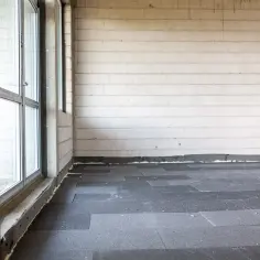 Na podłodze w stanie surowym ułożono płyty styropianowe, przygotowując grunt pod dalsze prace. To pierwszy krok, jak układać styropian na podłodze.