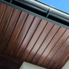 Brązowa podbitka z widocznymi otworami wentylacyjnymi, co ile są rozmieszczone, pod szarym rynna.