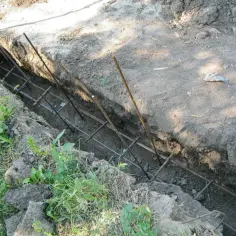 Wygląda na to, że koparka wyznacza, jak głęboko fundament pod ogrodzenie powinien sięgać. W wykopie widać zbrojenie.