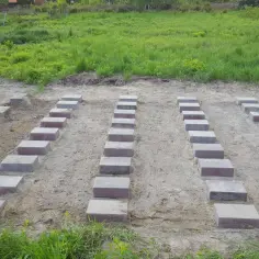 Przygotowany teren pod garaż blaszany. Ułożone bloczki betonowe tworzą fundament.