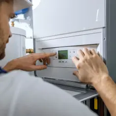 Instalator sprawdza ustawienia kotła gazowego. Zastanawiasz się, ile kosztuje założenie podlicznika gazu?