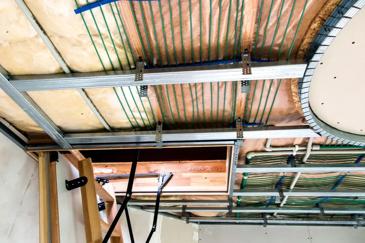 Instalacja ogrzewania sufitowego wodnego z zielonymi rurkami, izolacją i metalowym stelażem.