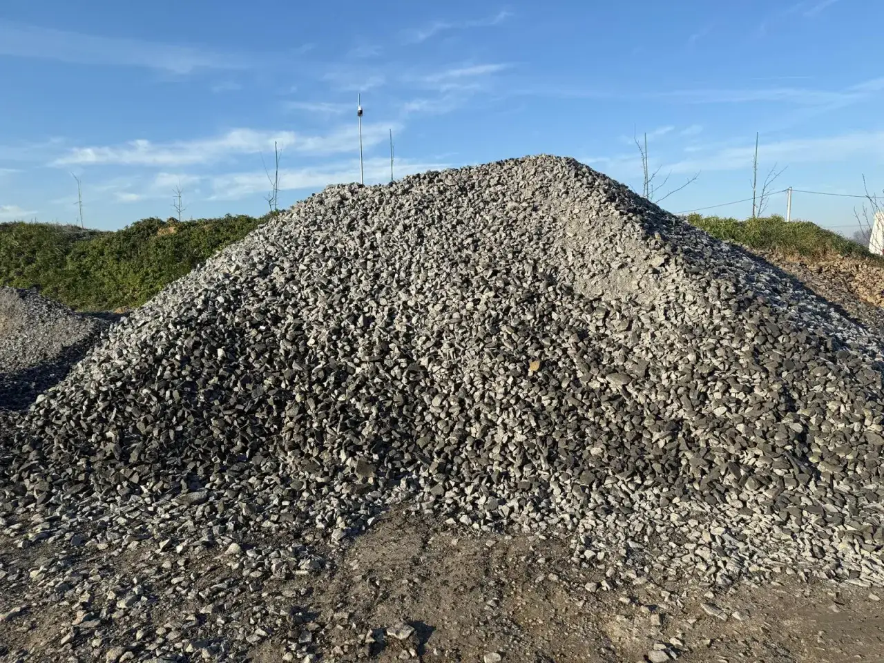 Ogromna hałda kruszywa do betonu pod błękitnym niebem. Materiał budowlany gotowy do użycia.