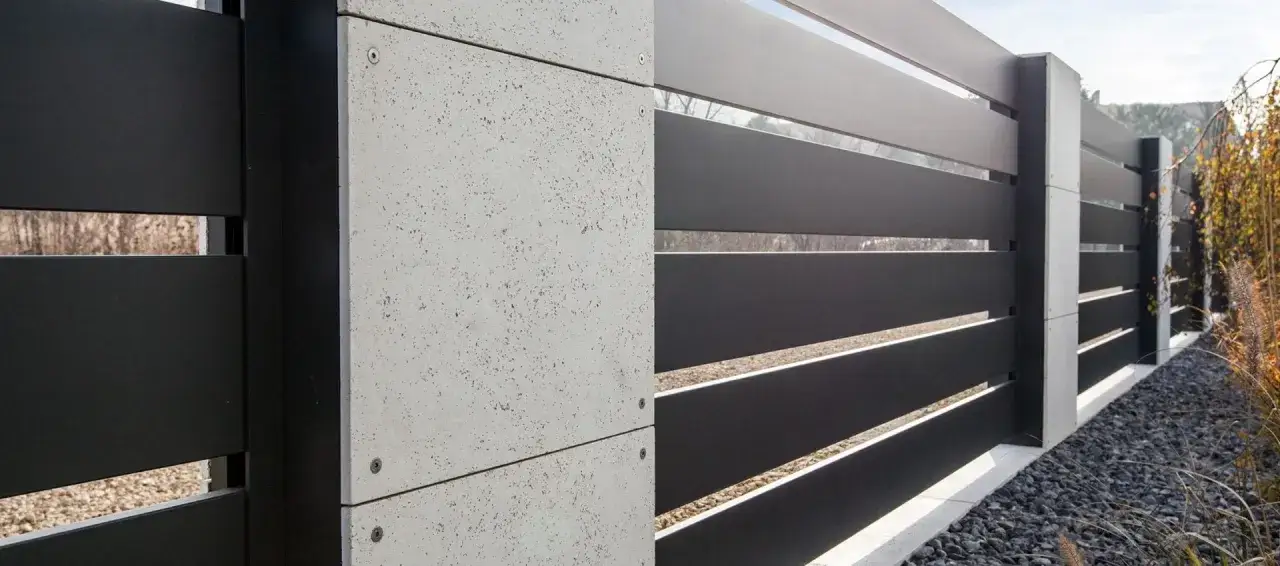 Nowoczesne ogrodzenie z czarnych paneli i betonowych słupków. Zastanawiasz się, ile kosztuje ogrodzenie metalowe?