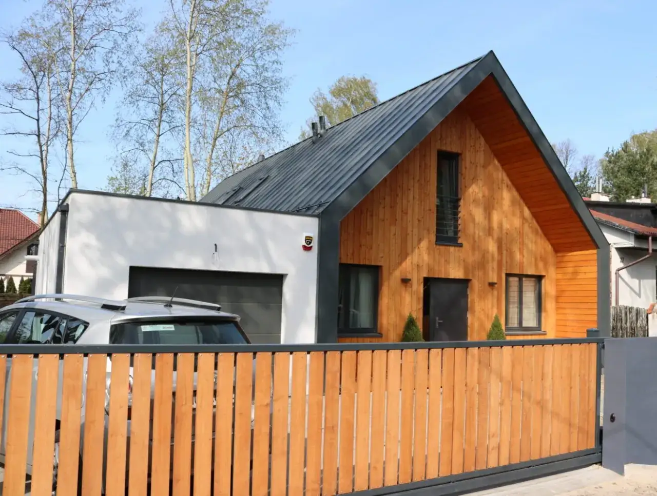 Nowoczesna dobudówka do starego domu, projekty uwzględniające drewnianą elewację i szary dach.