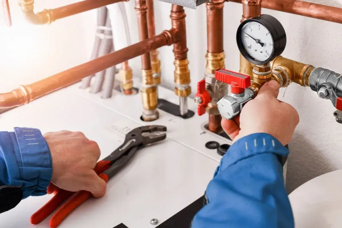 Instalator reguluje zawór przy instalacji gazowej. Zastanawiasz się, ile kosztuje przyłącze gazu?