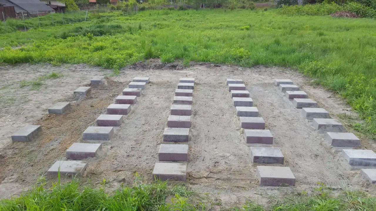 Ułożone bloczki betonowe tworzą fundament pod przyszły garaż blaszany.