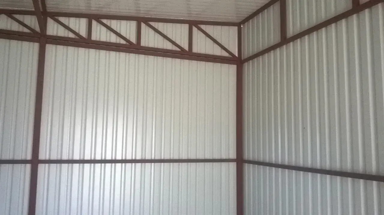 Wnętrze garażu blaszanego z widoczną konstrukcją i falistymi ścianami. Trwają prace nad ociepleniem garazu blaszanego.
